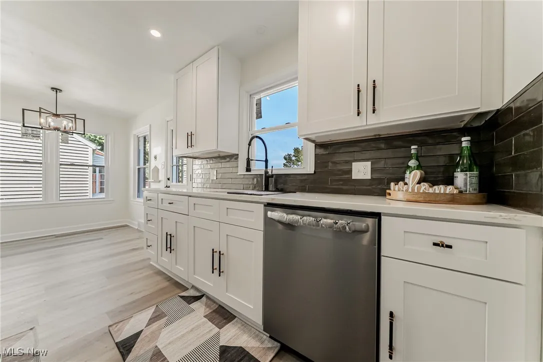 Kitchen featuring tasteful backsplash, white cabinets, dishwasher, recessed lighting, and decorative light fixtures