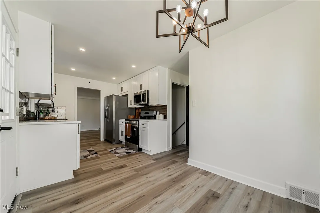 Kitchen featuring white cabinetry, backsplash, appliances with stainless steel finishes, light wood finished floors, and recessed lighting