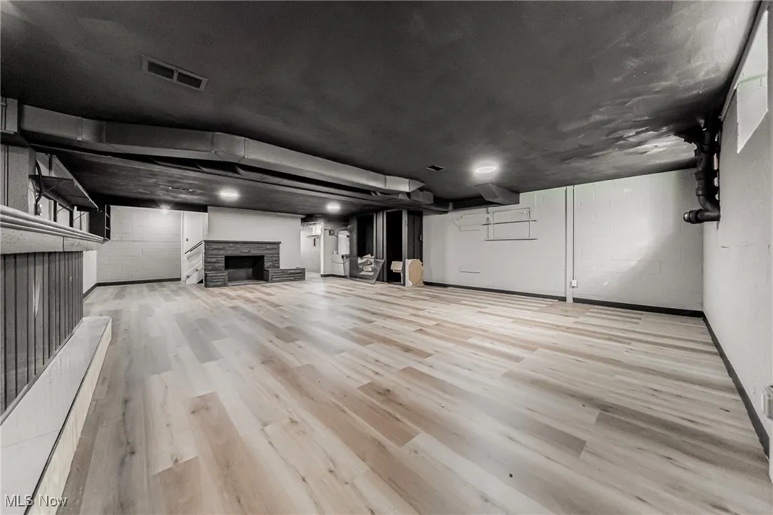 Finished below grade area featuring a fireplace and light wood-style flooring