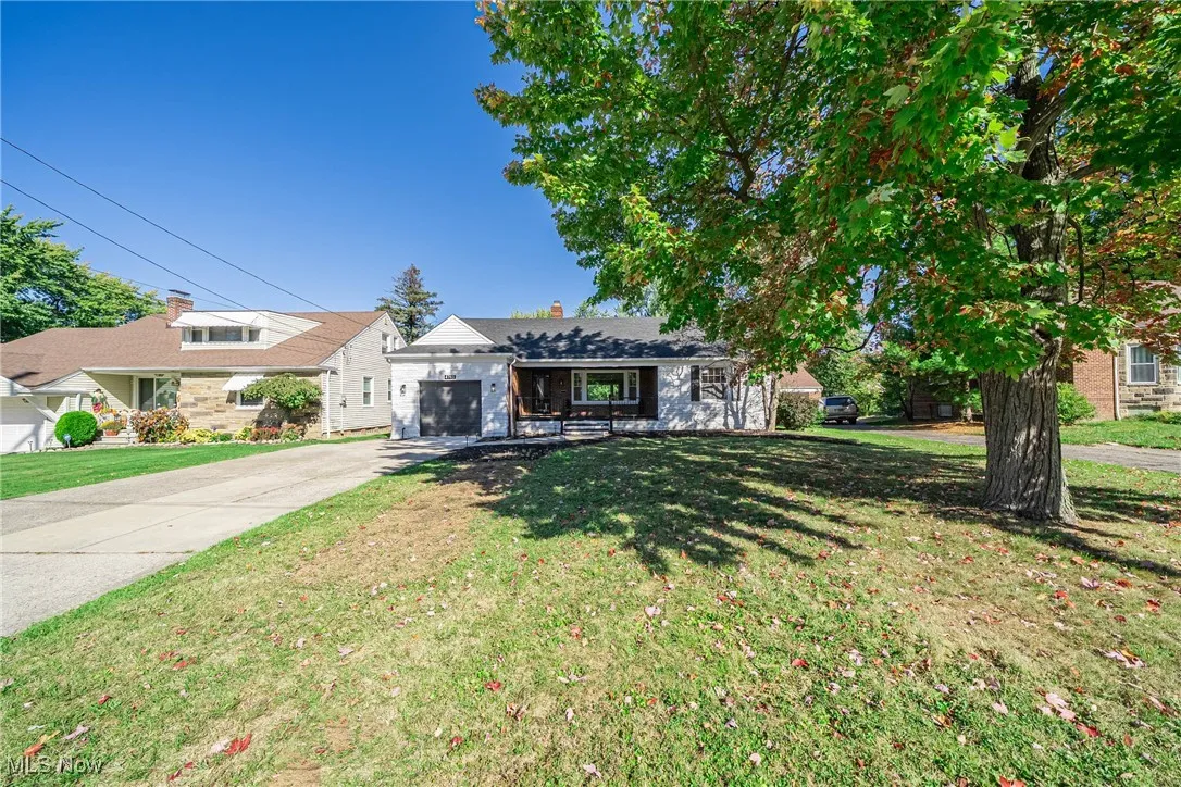 View of front of house featuring a chimney, driveway, a front yard, and an attached garage