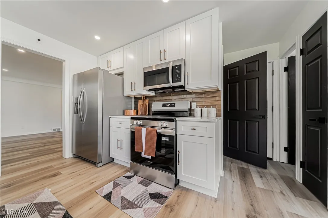 Kitchen featuring appliances with stainless steel finishes, white cabinets, light wood-type flooring, and recessed lighting