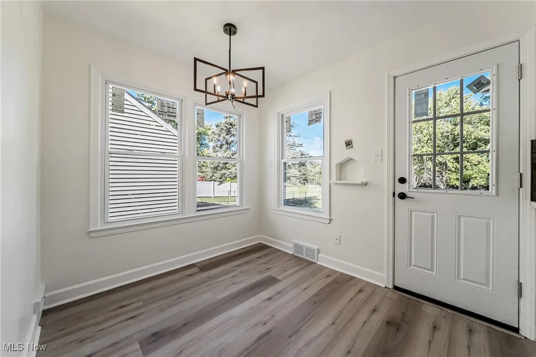Unfurnished dining area with wood finished floors, plenty of natural light, and a chandelier