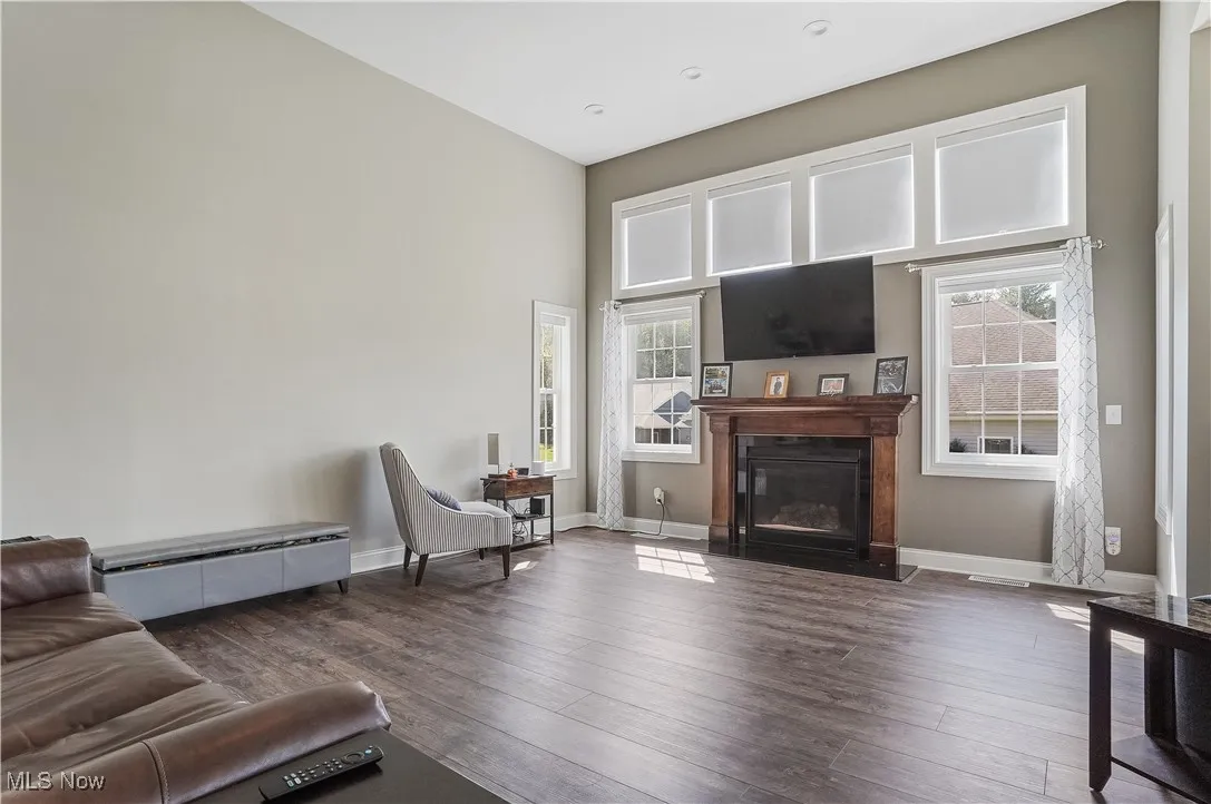 Living room with wood finished floors, a fireplace with flush hearth, and a high ceiling