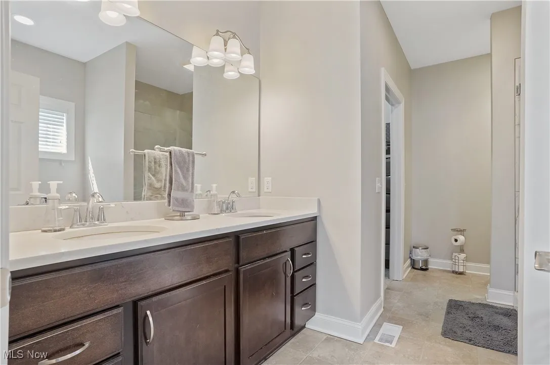Bathroom with double vanity, tile patterned flooring, a shower, and a chandelier
