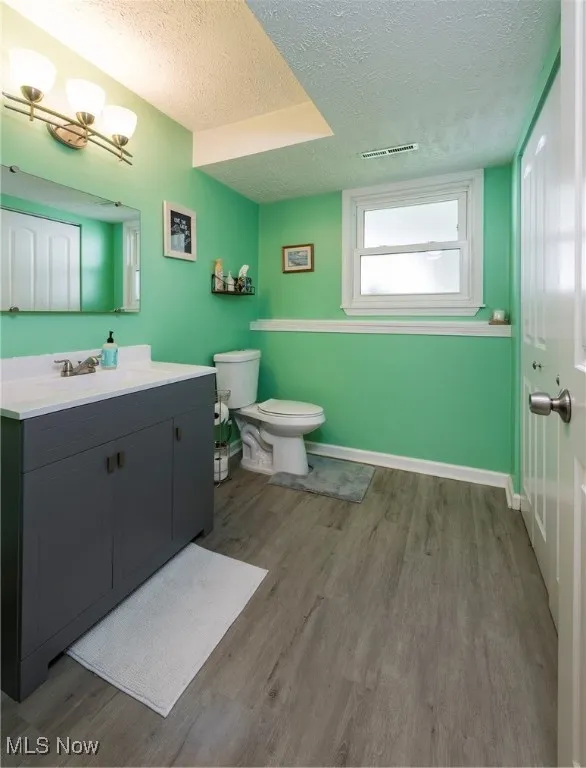 Lower level half bath featuring vanity, luxury vinyl wood look flooring and shares space with the laundry area.