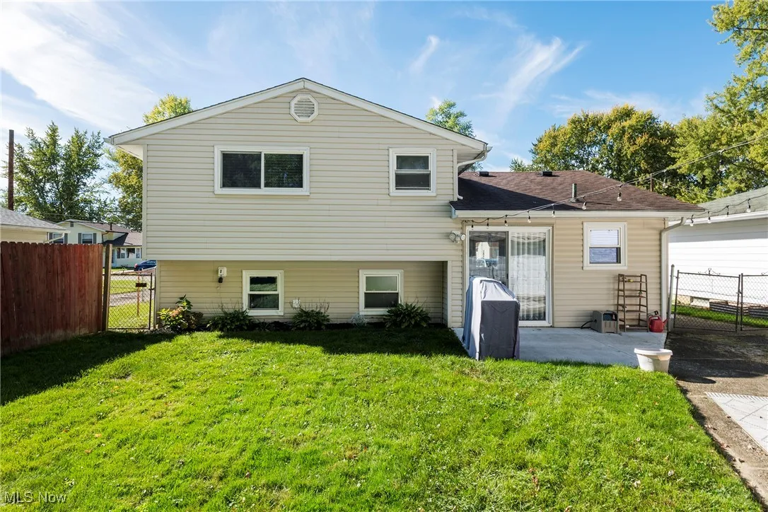 Rear view of property featuring a patio with sliders from kitchen and fenced backyard