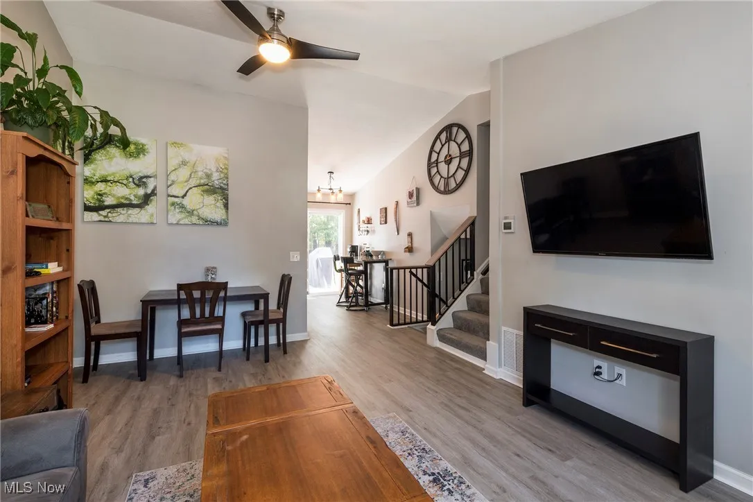 Living room/dining room combo featuring luxury vinyl wood look flooring, high ceiling, a ceiling fan, view into kitchen and view of upper and lower level stairs