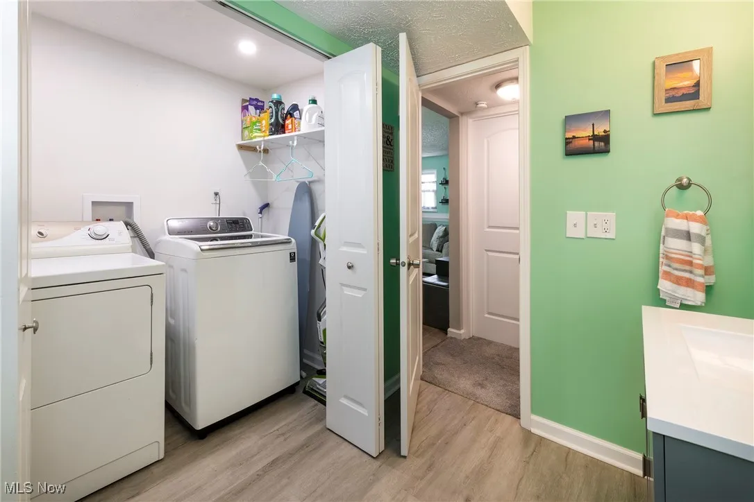 Lower level laundry area shares space with half bath featuring luxury vinyl wood look flooring. Washer and dryer stay.