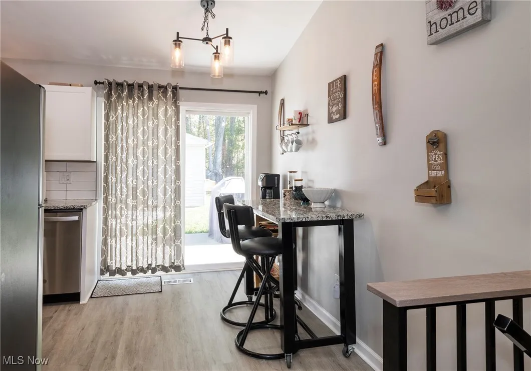 Kitchen eating area, sliders to backyard, chandelier, granite topped movable island table (that stays) and luxury vinyl wood look flooring