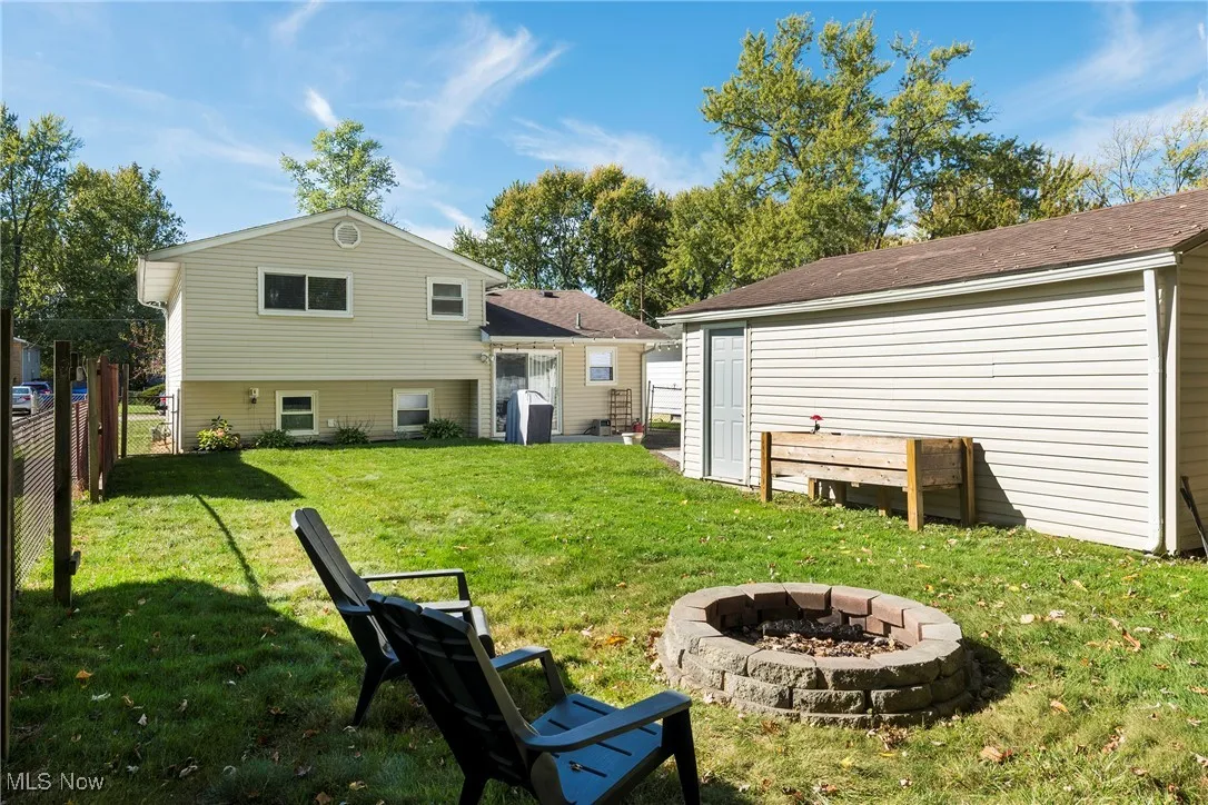 Back of home with view of fenced backyard, fire pit and two-car detached​​‌​​​​‌​​‌‌​‌‌​​​‌‌​‌​‌​‌​​​‌​​ garage