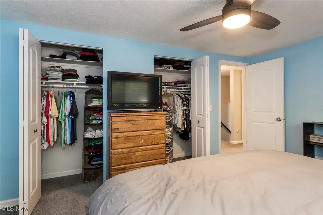 Carpeted primary bedroom with his and her closets and ceiling fan/overhead light. King sized bed fits in this room.