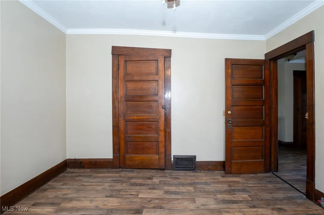 Bedroom featuring crown molding and dark wood finished floors