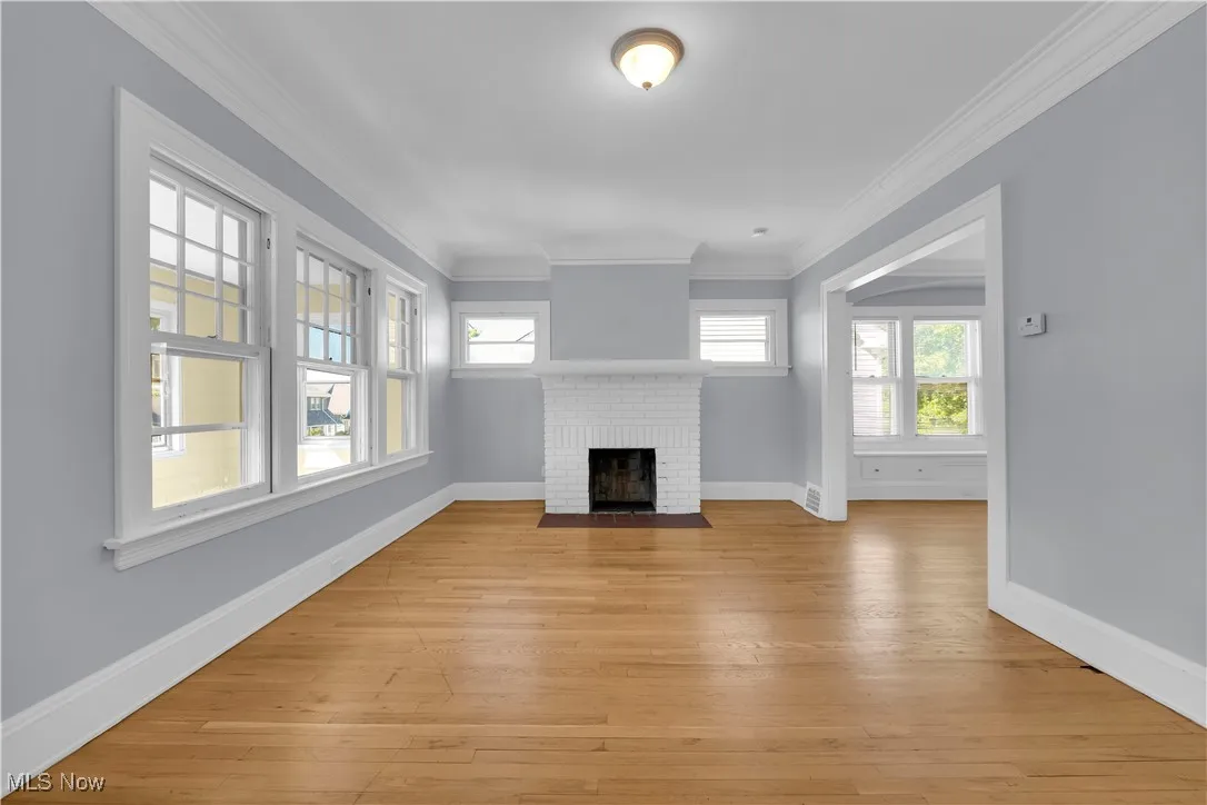 Unfurnished living room with crown molding, light wood-style flooring, and a fireplace