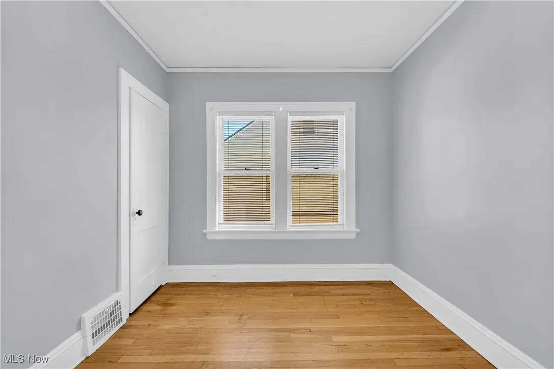 Empty room featuring crown molding and light wood finished floors