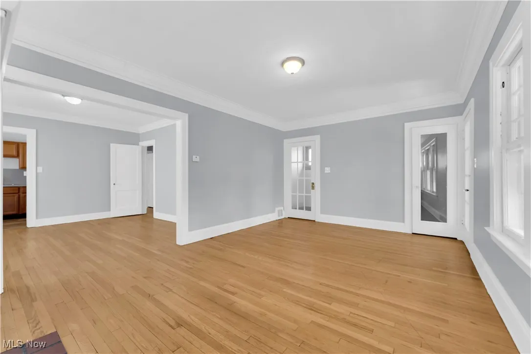 Empty room with crown molding and light wood-style flooring