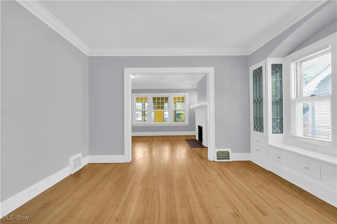 Spare room featuring crown molding, light wood-style flooring, and a fireplace