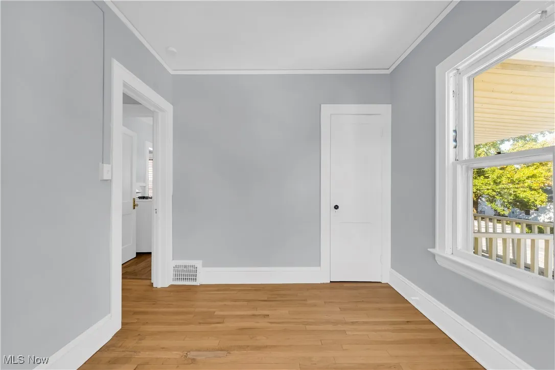Empty room featuring light wood-style flooring and ornamental molding