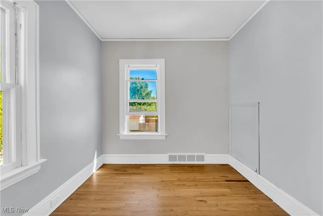 Empty room with crown molding and light wood-type flooring