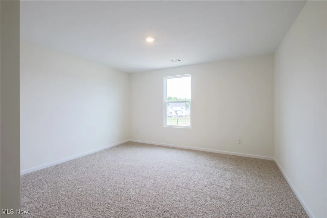 Unfurnished room featuring light carpet and baseboards