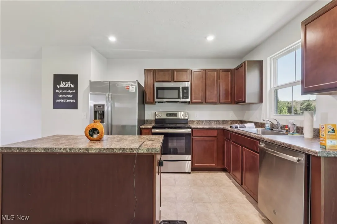 Kitchen with appliances with stainless steel finishes, a center island, recessed lighting, and dark brown cabinetry