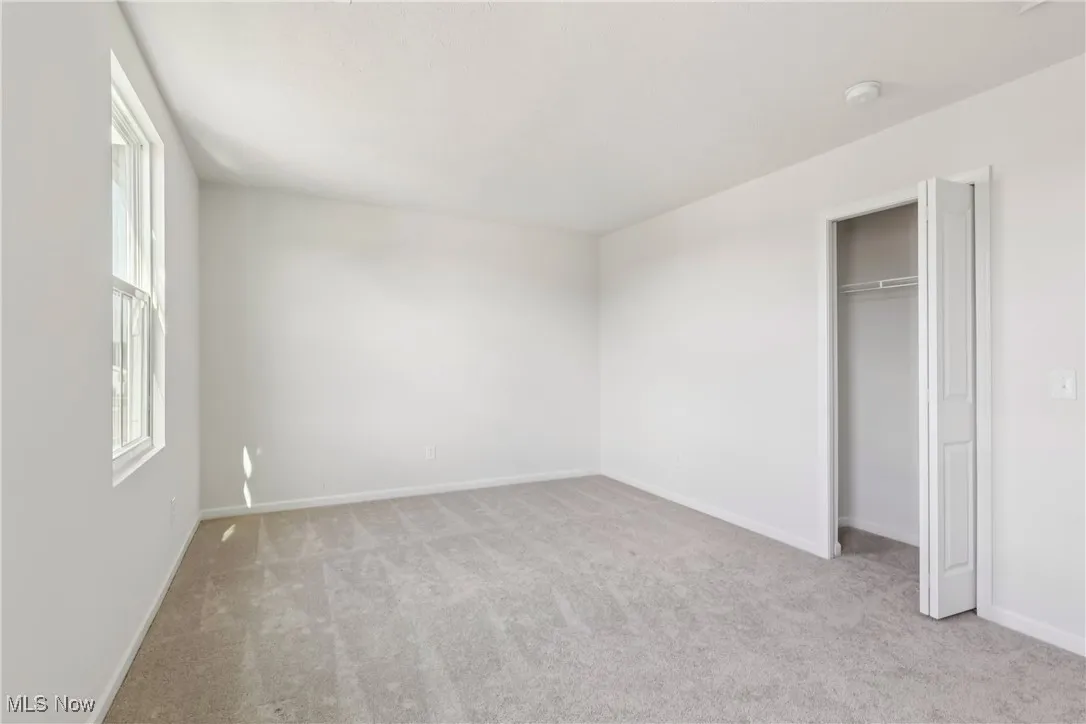 Unfurnished bedroom with light carpet and a closet