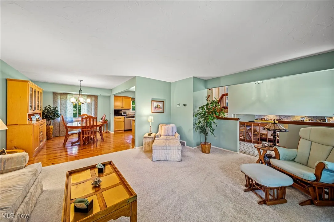 Living room with light carpet, a chandelier, and light wood finished floors