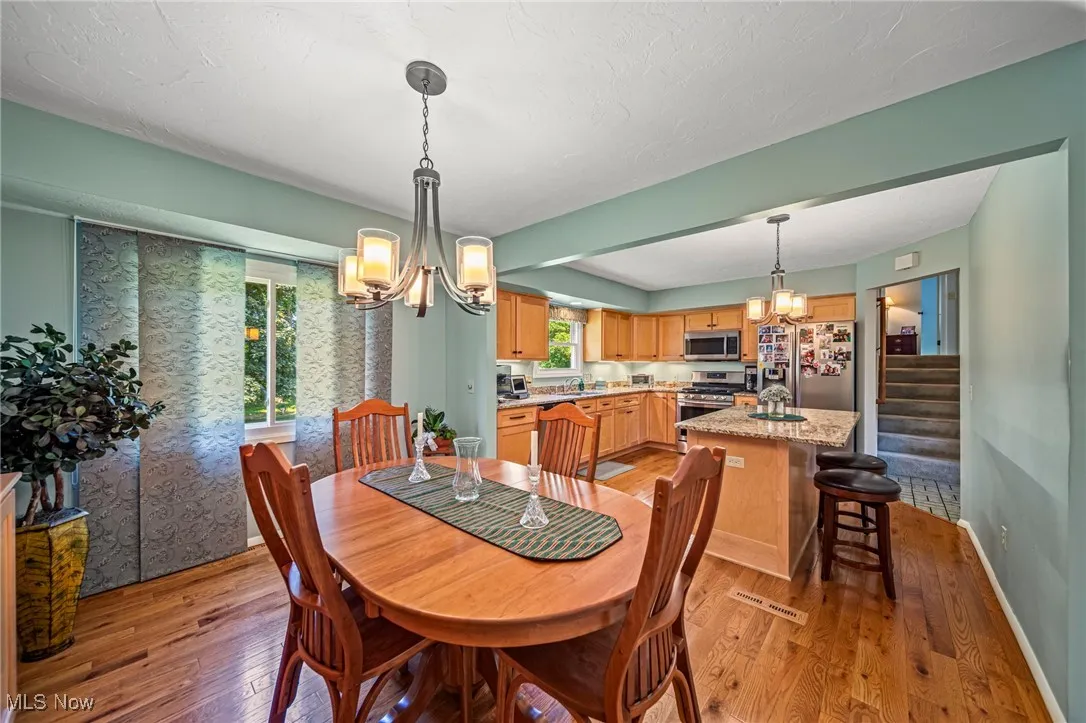 Dining space featuring a chandelier, light wood-type flooring, stairway, and a textured ceiling