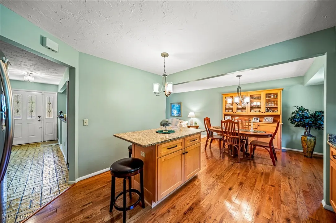 Kitchen with a textured ceiling, a center island, light stone countertops, dark wood finished floors, and a kitchen breakfast bar