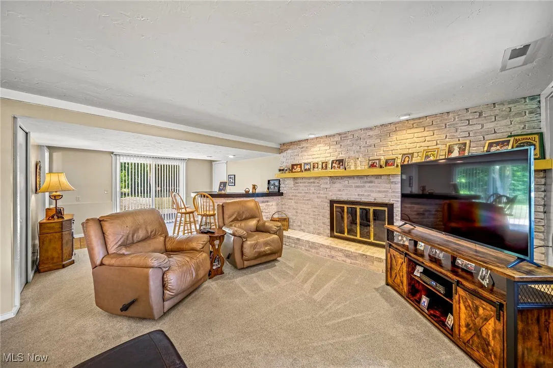 Carpeted living room with brick wall, a brick fireplace, and a textured ceiling