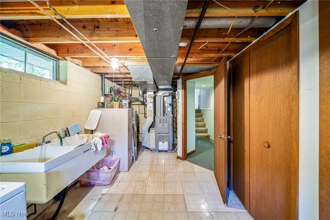 Below grade area with light flooring, stairway, heating unit, and washer / clothes dryer