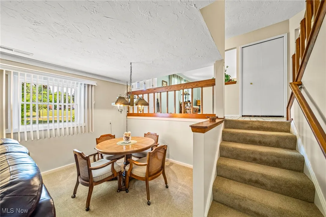 Dining space with carpet flooring, a textured ceiling, and stairway