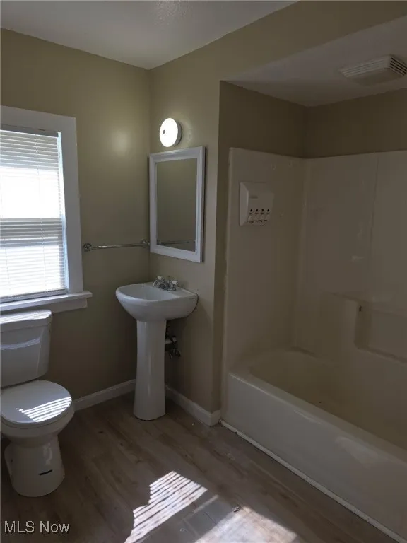 Bathroom with light wood-style floors, shower / washtub combination, and a textured ceiling