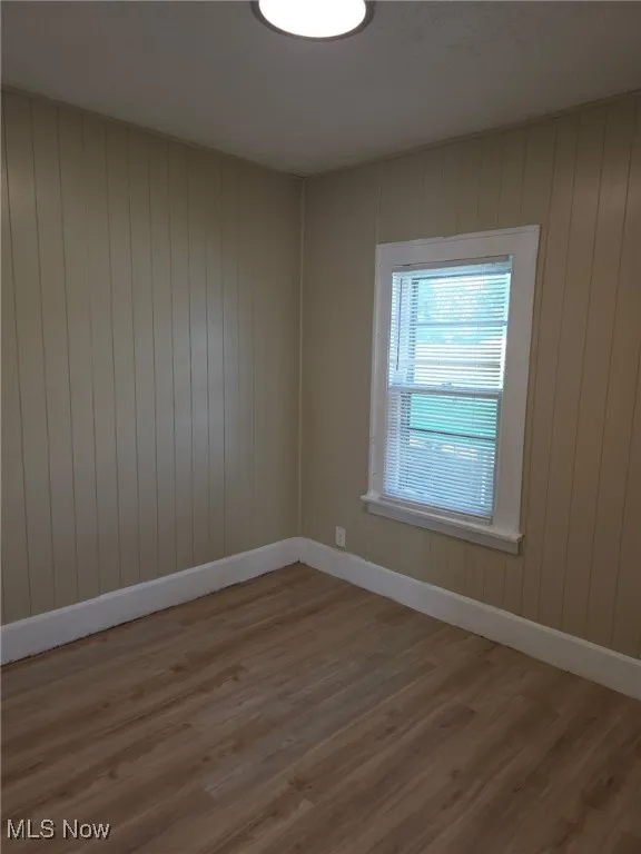 Unfurnished room featuring wood finished floors and wood walls