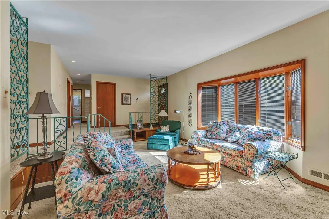 Living room with windows at the front overlooking front yard and light colored carpeting.