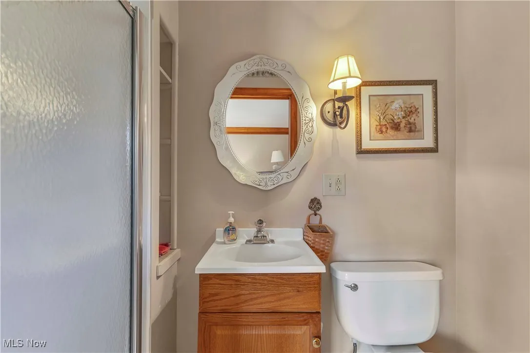Primary bathroom attached to primary bedroom featuring updated vanity with mirror above, toilet and walk in shower.