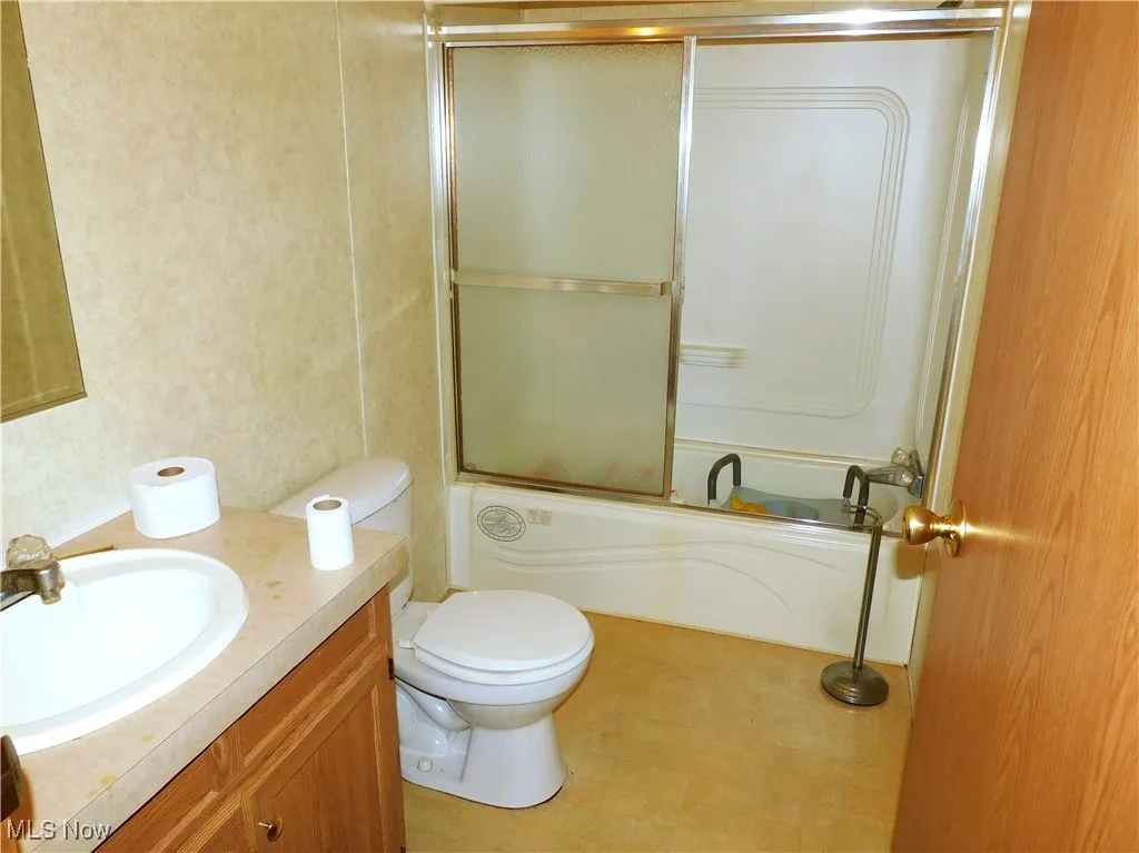 Full bath featuring shower / bath combination with glass door and vanity