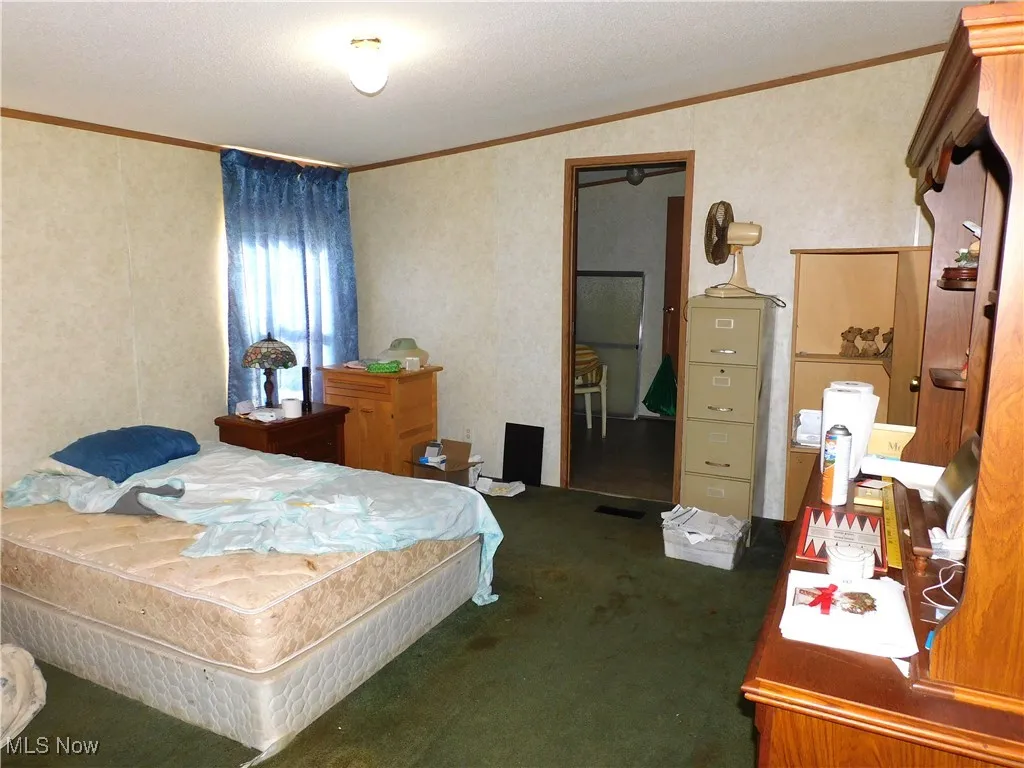 Bedroom with ornamental molding, carpet floors, and a textured ceiling