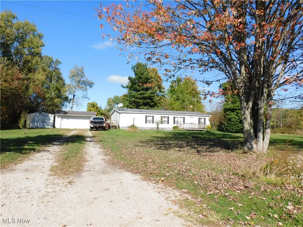 View of front of home with a front yard, an outbuilding, and driveway