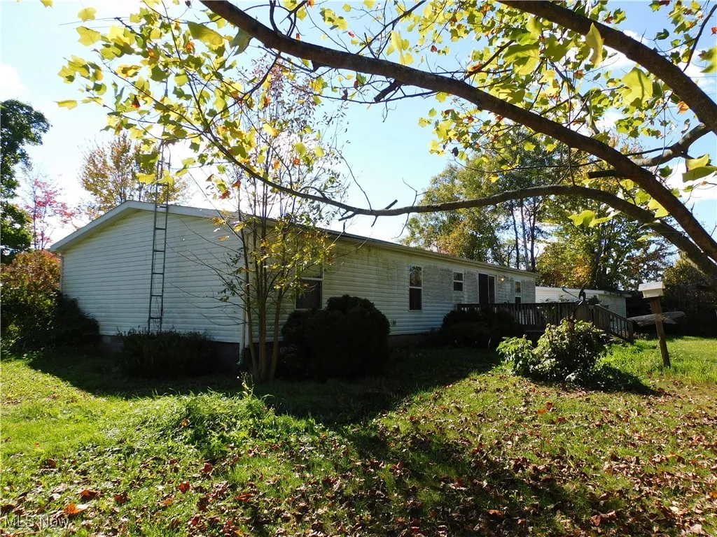 Back of house featuring a lawn and a deck