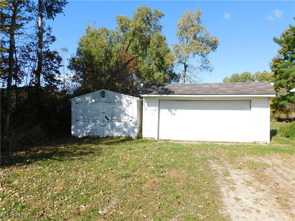 View of side of home featuring a lawn, a garage, and a storage unit