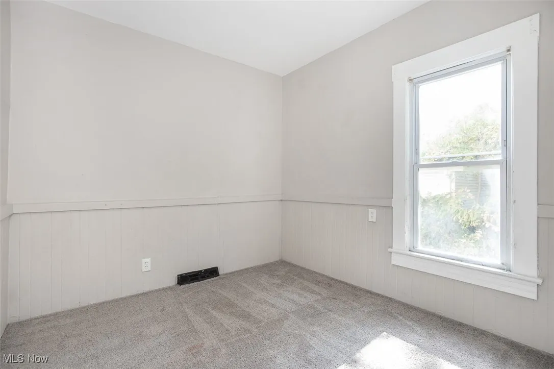 Carpeted empty room with a wainscoted wall