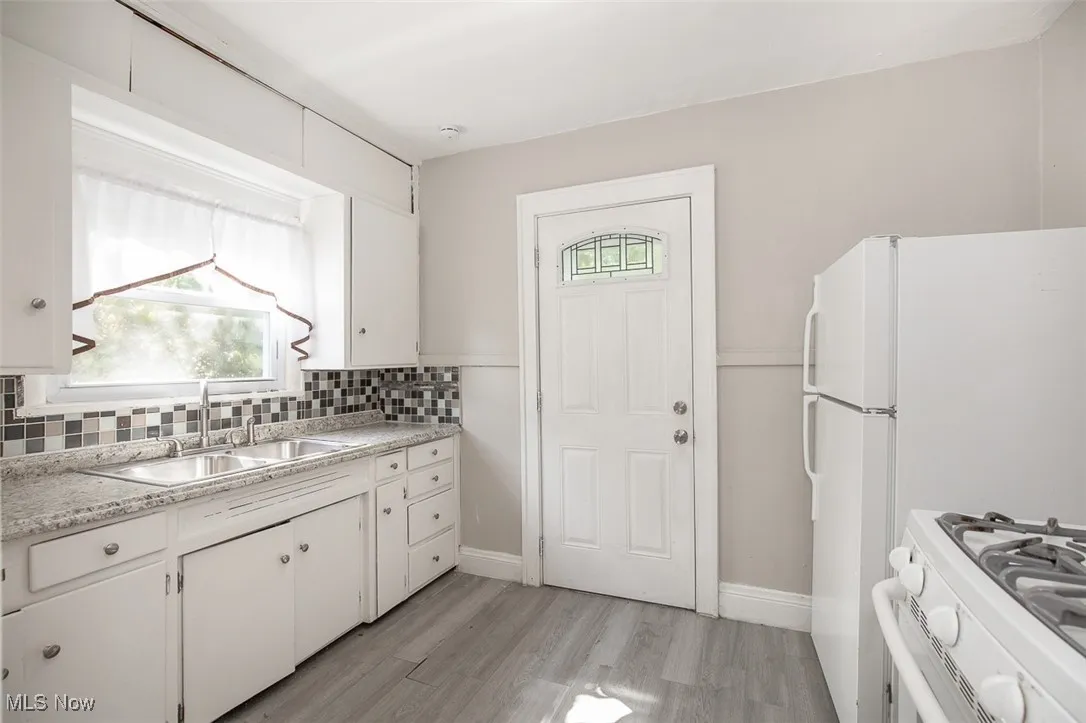 Kitchen featuring white cabinets, light countertops, light wood-style floors, and tasteful backsplash