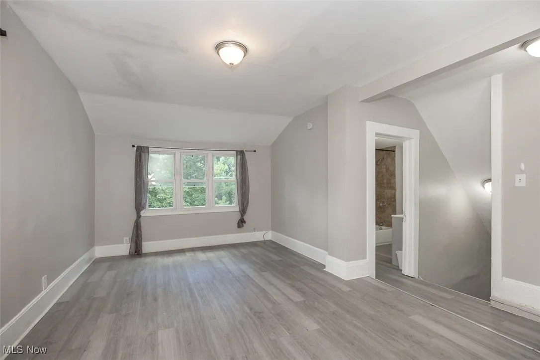 Bonus room with vaulted ceiling and light wood-style flooring