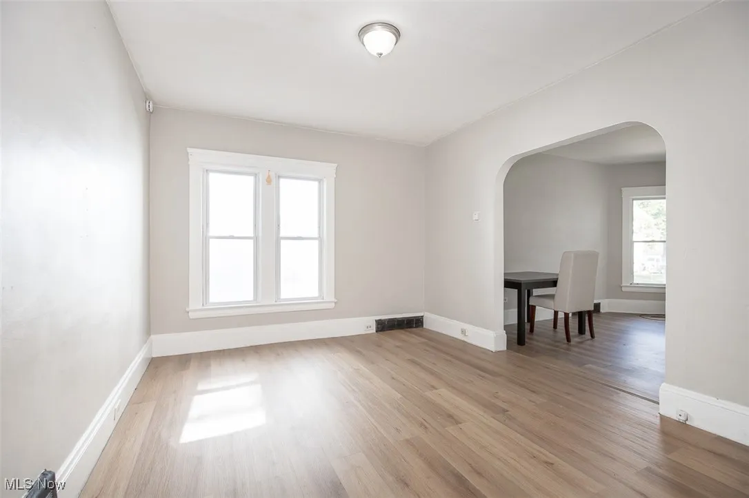Unfurnished room featuring arched walkways and light wood finished floors