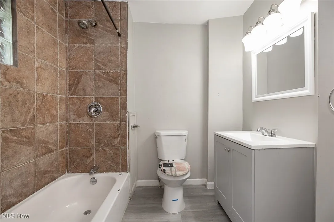 Bathroom with bathing tub / shower combination, vanity, and light wood-style floors