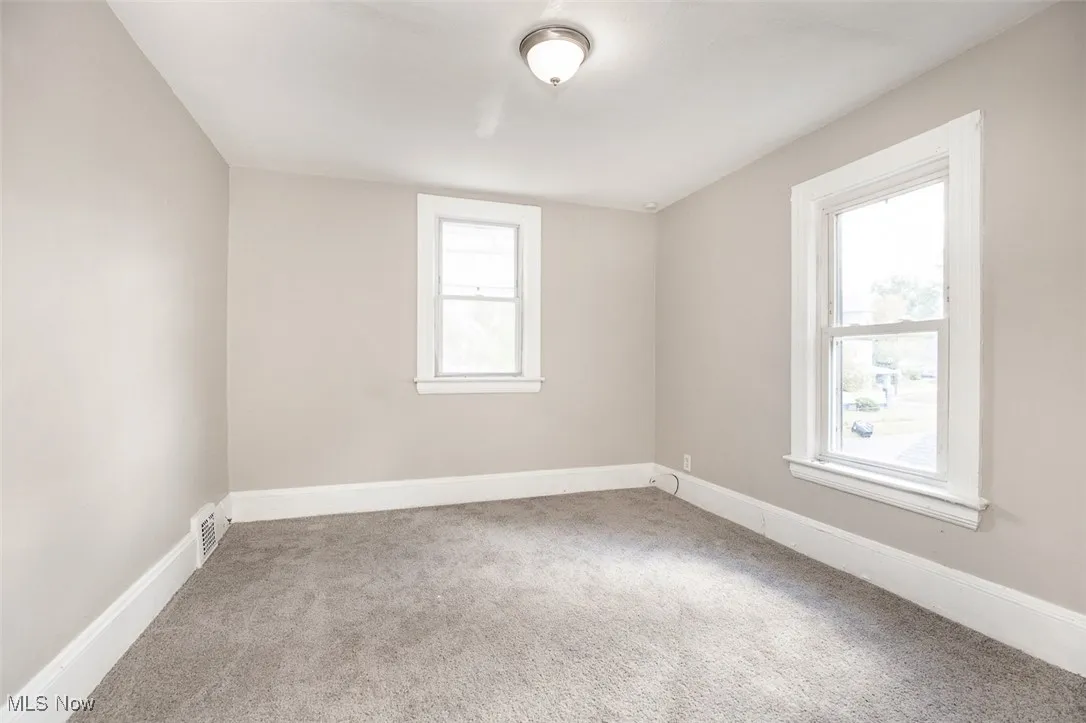 Empty room with light colored carpet and baseboards