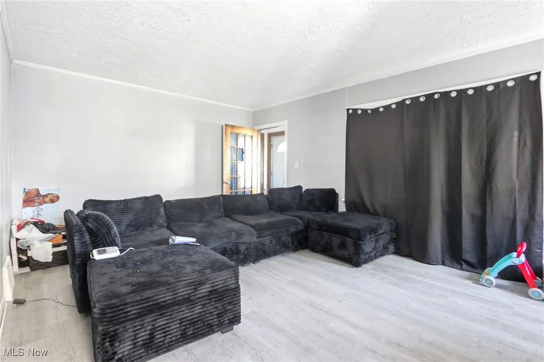 Living area with a textured ceiling, wood finished floors, and ornamental molding