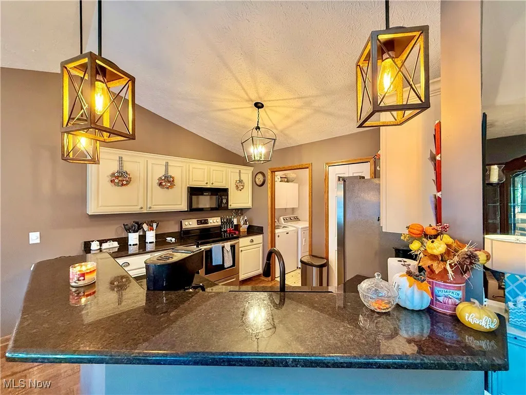 Kitchen featuring stainless steel fridge, dishwasher and range, granite countertops and decorative light fixtures