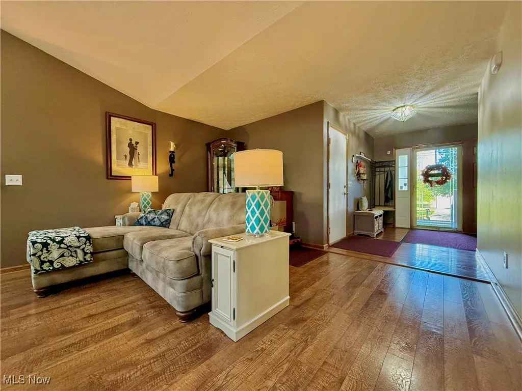 Living area with luxury vinyl wood look floors, lofted ceiling. Foyer has hard wood floors.