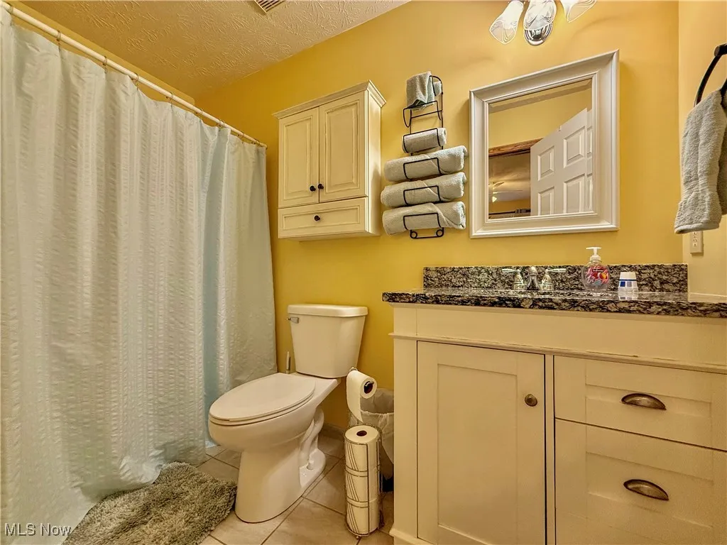 Second full bath featuring granite vanity, ceramic floors, and a tub shower combo
